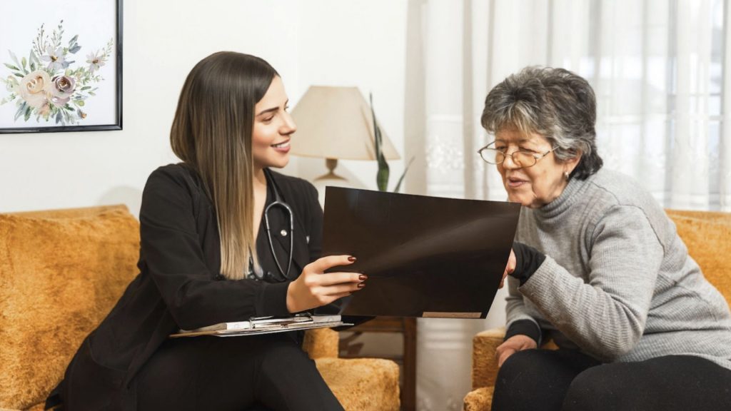 Médica de Marasalud a domicilio revisando resultados médicos con paciente adulto mayor durante consulta en casa