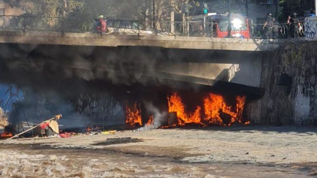 Persona en situación de calle quema su ruco durante operativo en el Río Mapocho