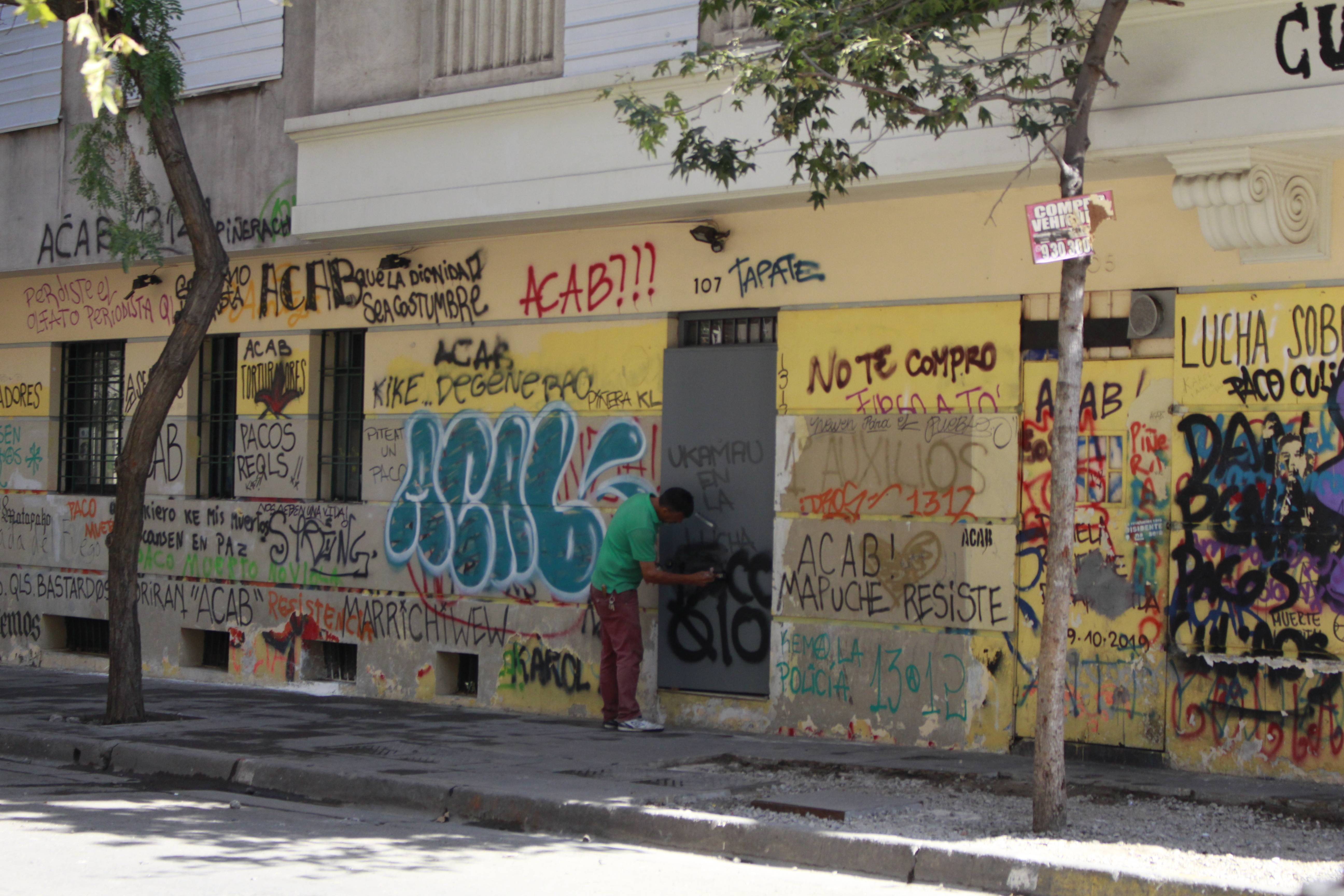 Un señor limpia graffitis de la puerta del edificio ubicado en la esquina de Irene Morales con Coronel Santiago Bueras. Créditos foto: PAUTA 