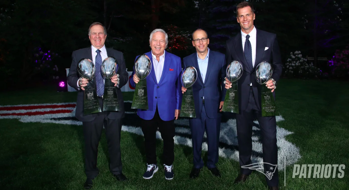 Robert Kraft, Bill Belichick y Josh McDaniels sostienen junto a Brady sus trofeos de SB. Créditos: patriots.com 